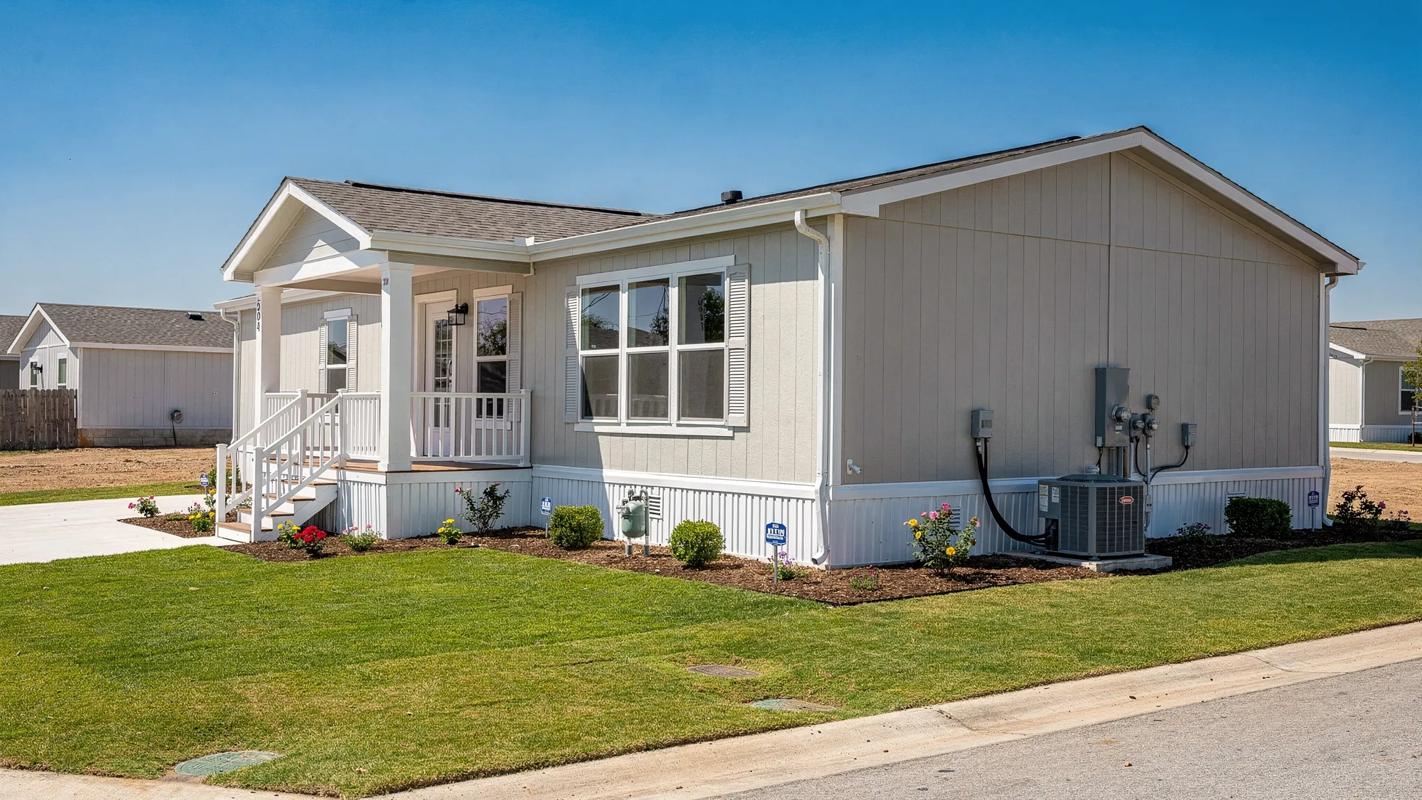 A modern manufactured home in San Antonio set on a prepared homesite with skirting, front steps, clean landscaping, and visible utility connections, showing what “move-in ready” installation looks like.