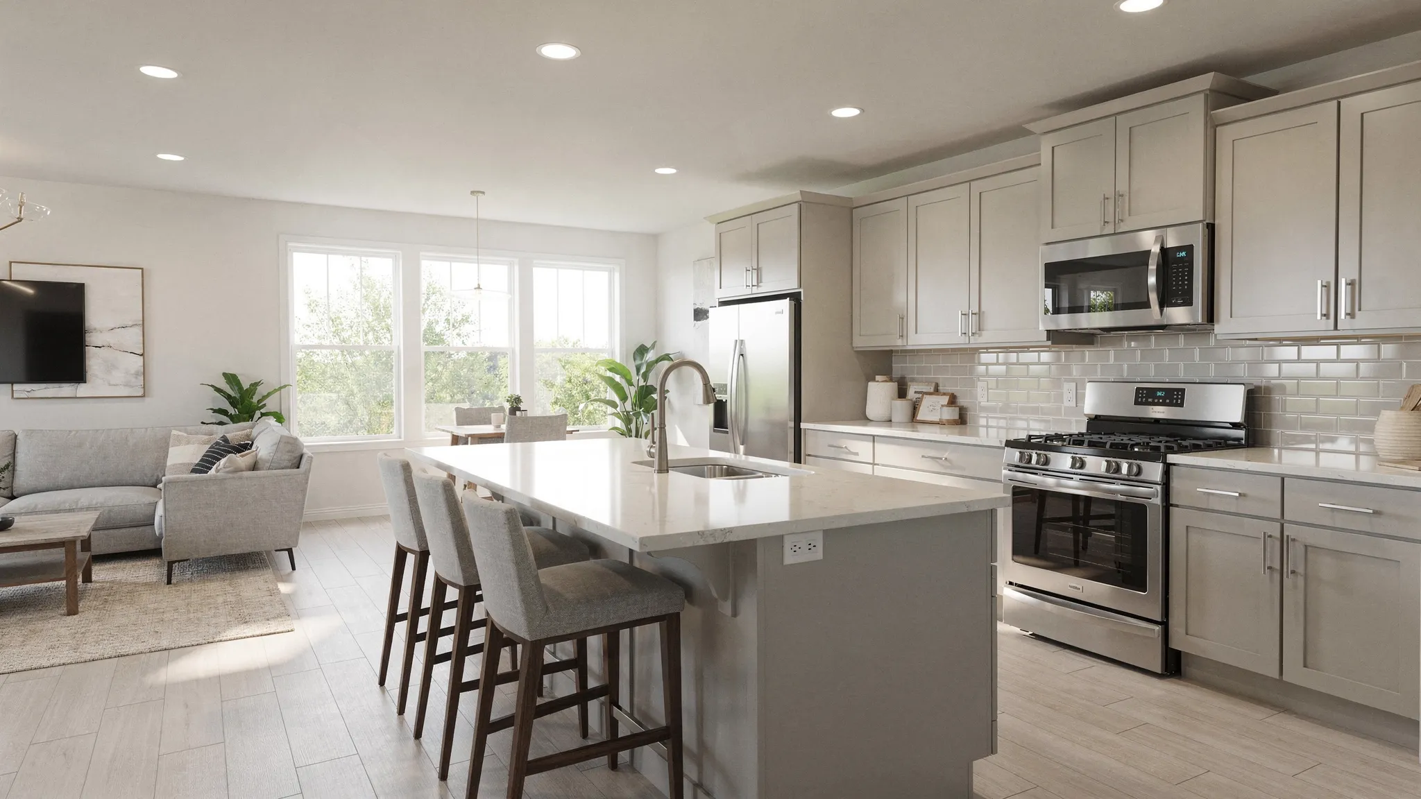 A bright manufactured home interior showing an open-concept living room and kitchen with a center island, modern cabinet fronts, recessed lighting, and large windows letting in daylight.