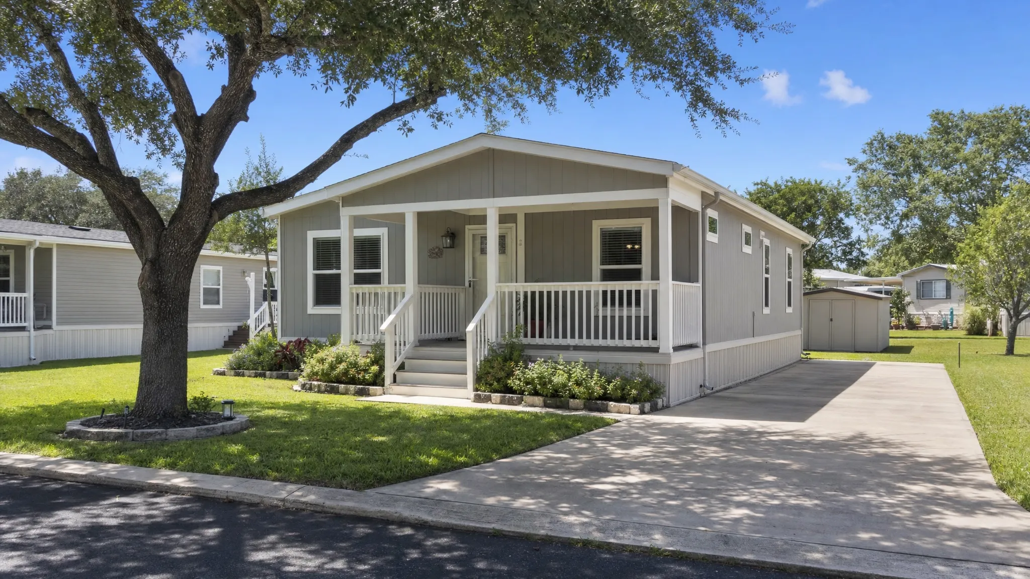 A clean manufactured home in a well-kept San Antonio community with a small front porch, driveway, trimmed lawn, and shade trees, showing a comfortable rental option in a quiet neighborhood.