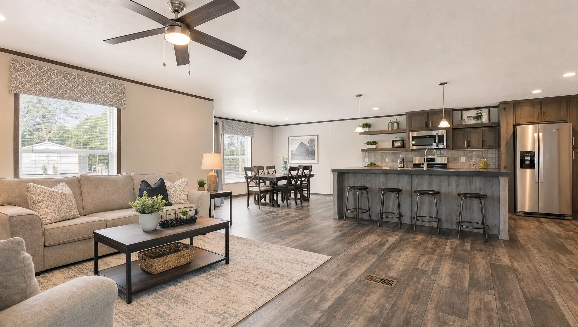 A spacious double wide manufactured home living area with an open kitchen, dining space, and natural light, showing a practical family-friendly layout with modern finishes.
