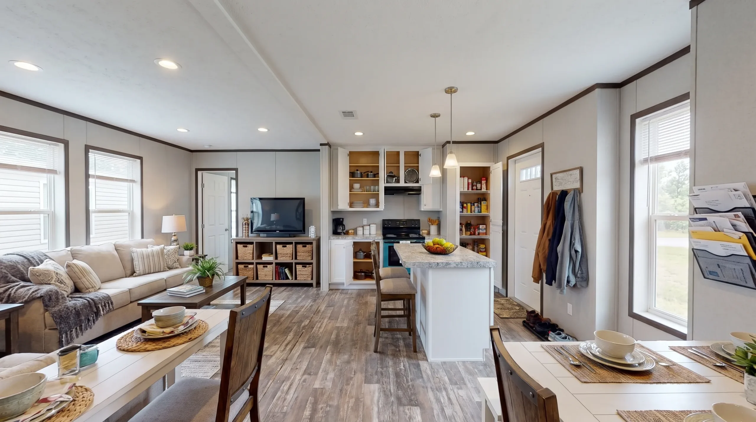 A bright manufactured home living room opens into the kitchen and dining area, showing storage, flow, and everyday livability.
