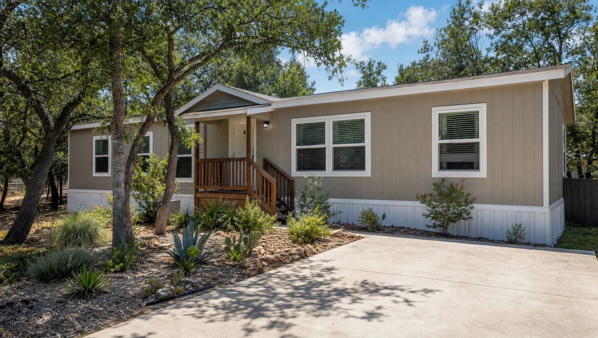 A manufactured home with a small porch, driveway, and native landscaping suggests an affordable Texas housing option.