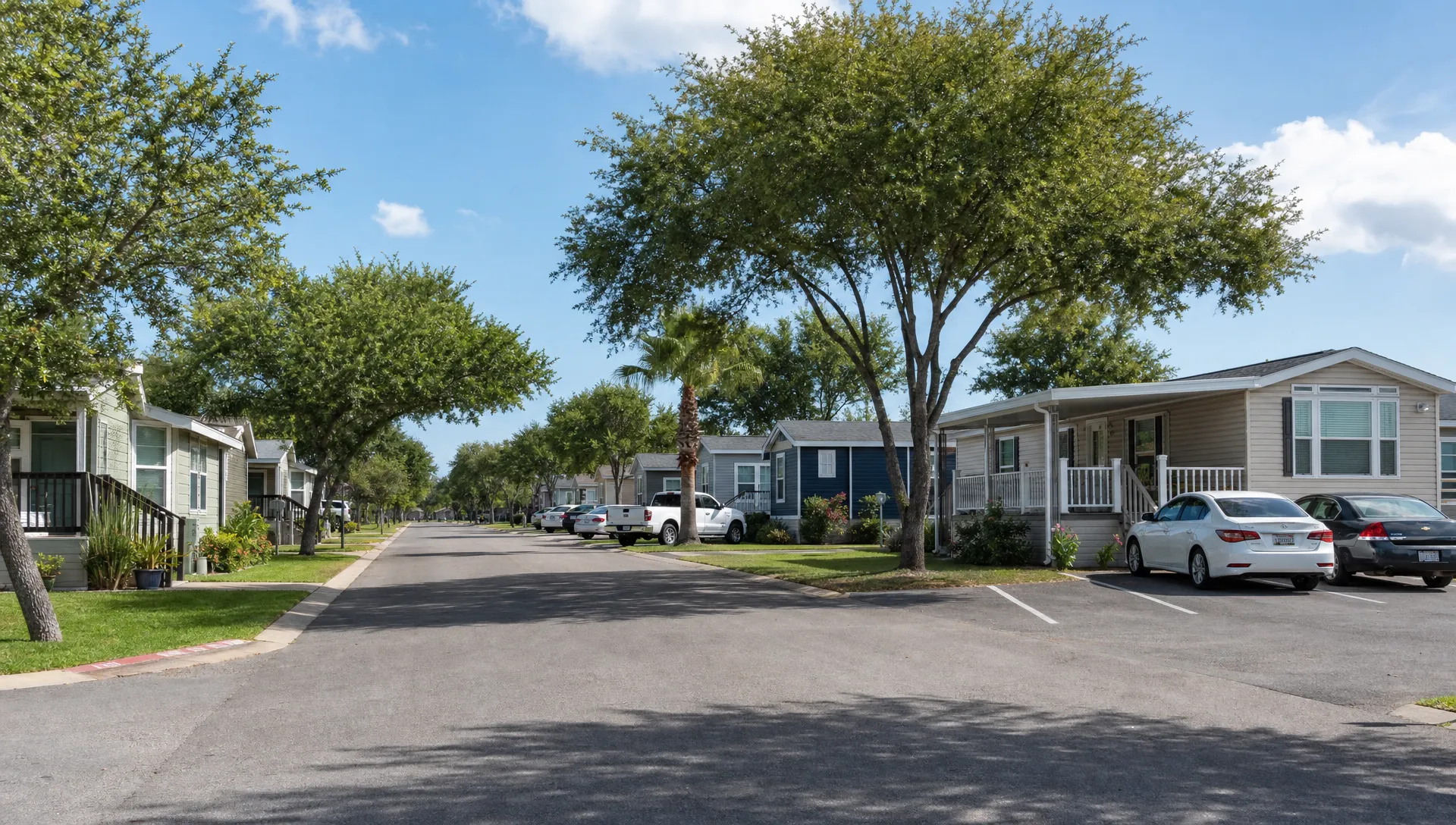 A well-kept manufactured home community in South Texas with modern homes, paved streets, shaded lots, parking spaces, and shared green areas.