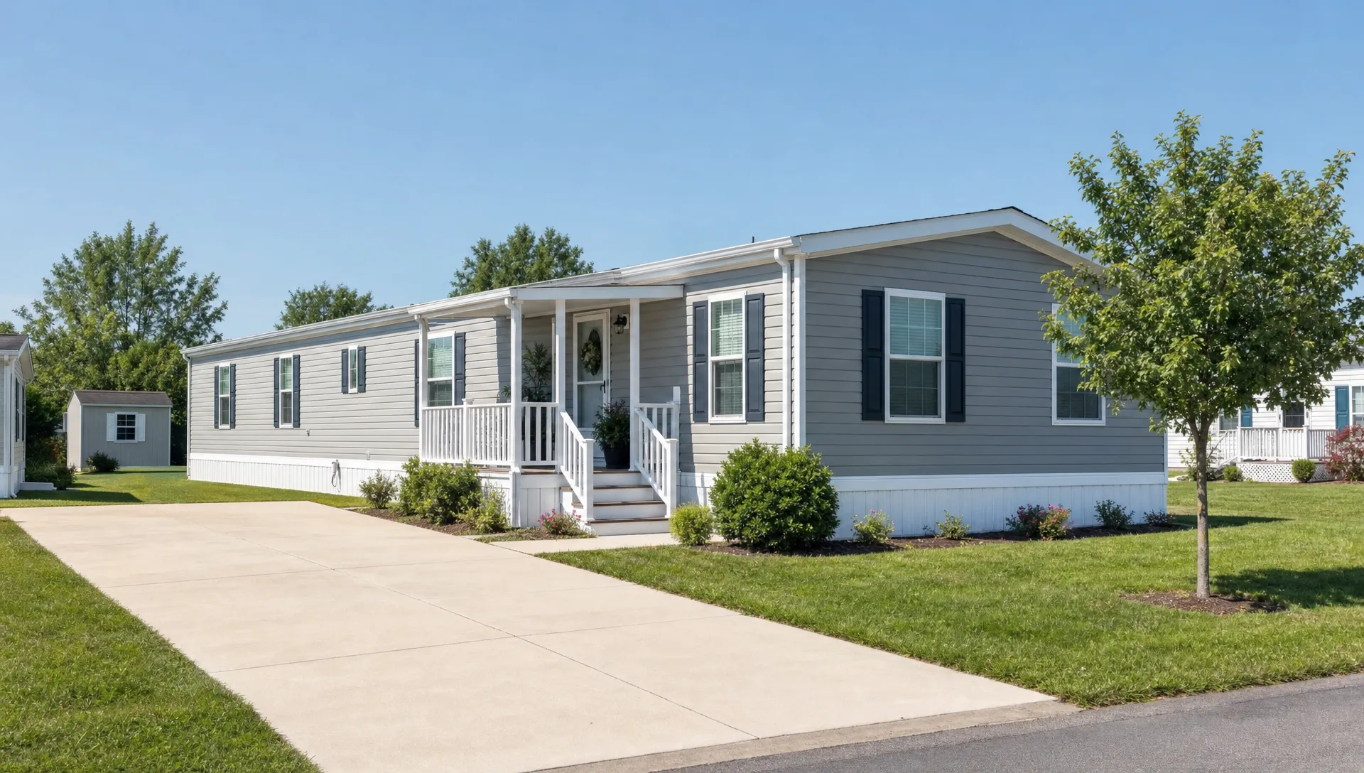 A well-maintained double wide manufactured home in a quiet community, with a small front porch, driveway, trimmed lawn and space for rental living.