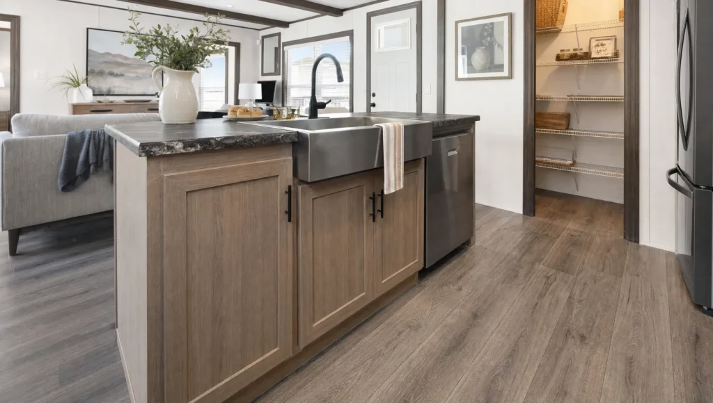 A manufactured home kitchen shows practical cabinets, storage, and durable finishes in a modern layout.