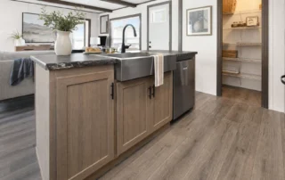 A manufactured home kitchen shows practical cabinets, storage, and durable finishes in a modern layout.