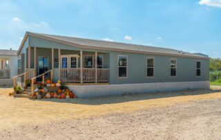 Front of the home with its covered porch and steps, on a newly graded lot