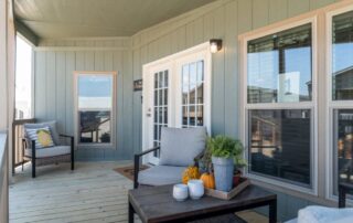 Covered front porch with seating, beadboard walls and French doors into the home