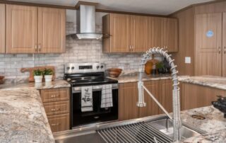 Kitchen range under a stainless hood, with a tile backsplash and deep sink