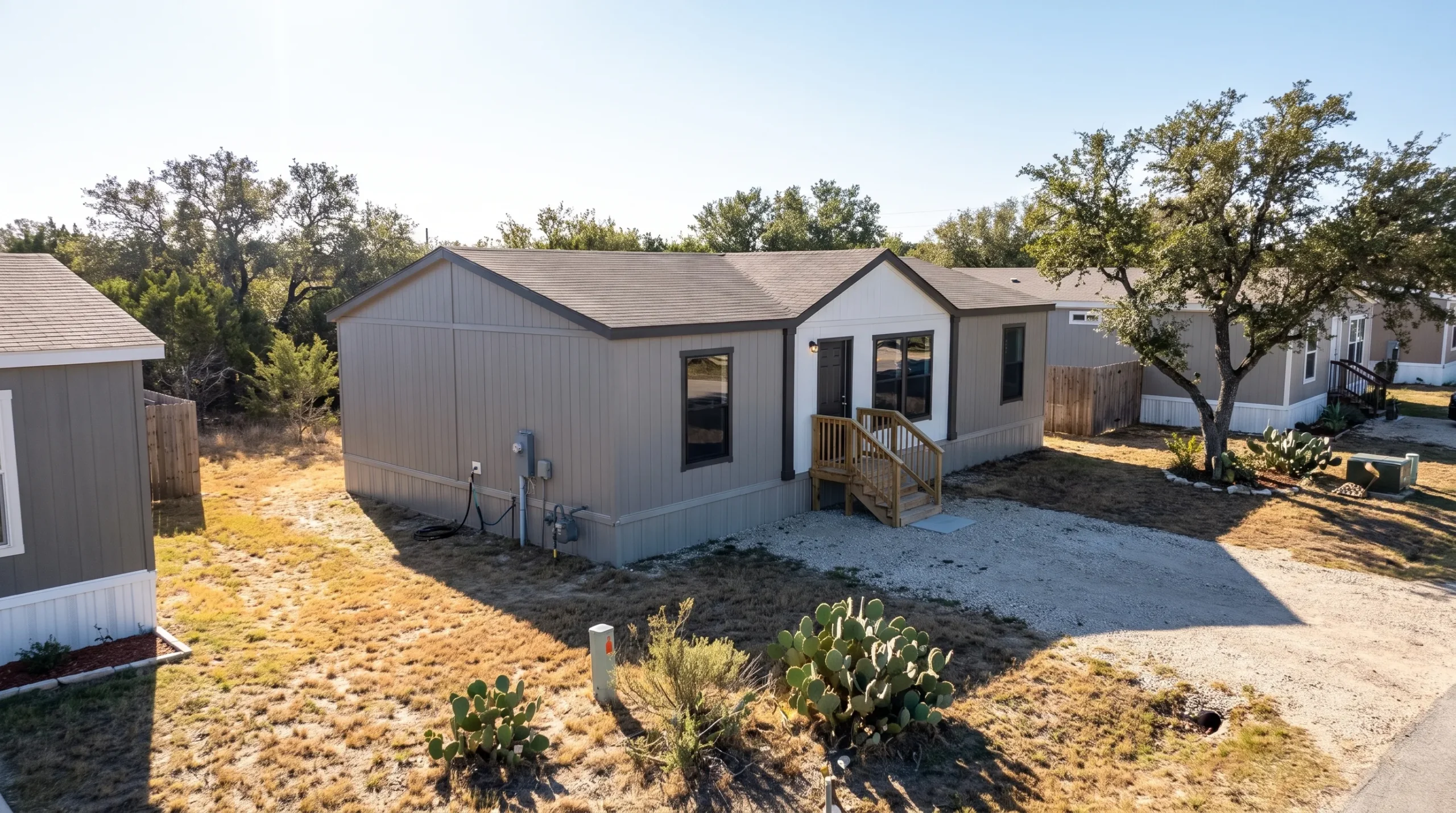 The Legacy Heritage H-3248-32A doublewide sits on a leased San Antonio community lot, with installed steps, utility connections, and neighboring homes nearby.